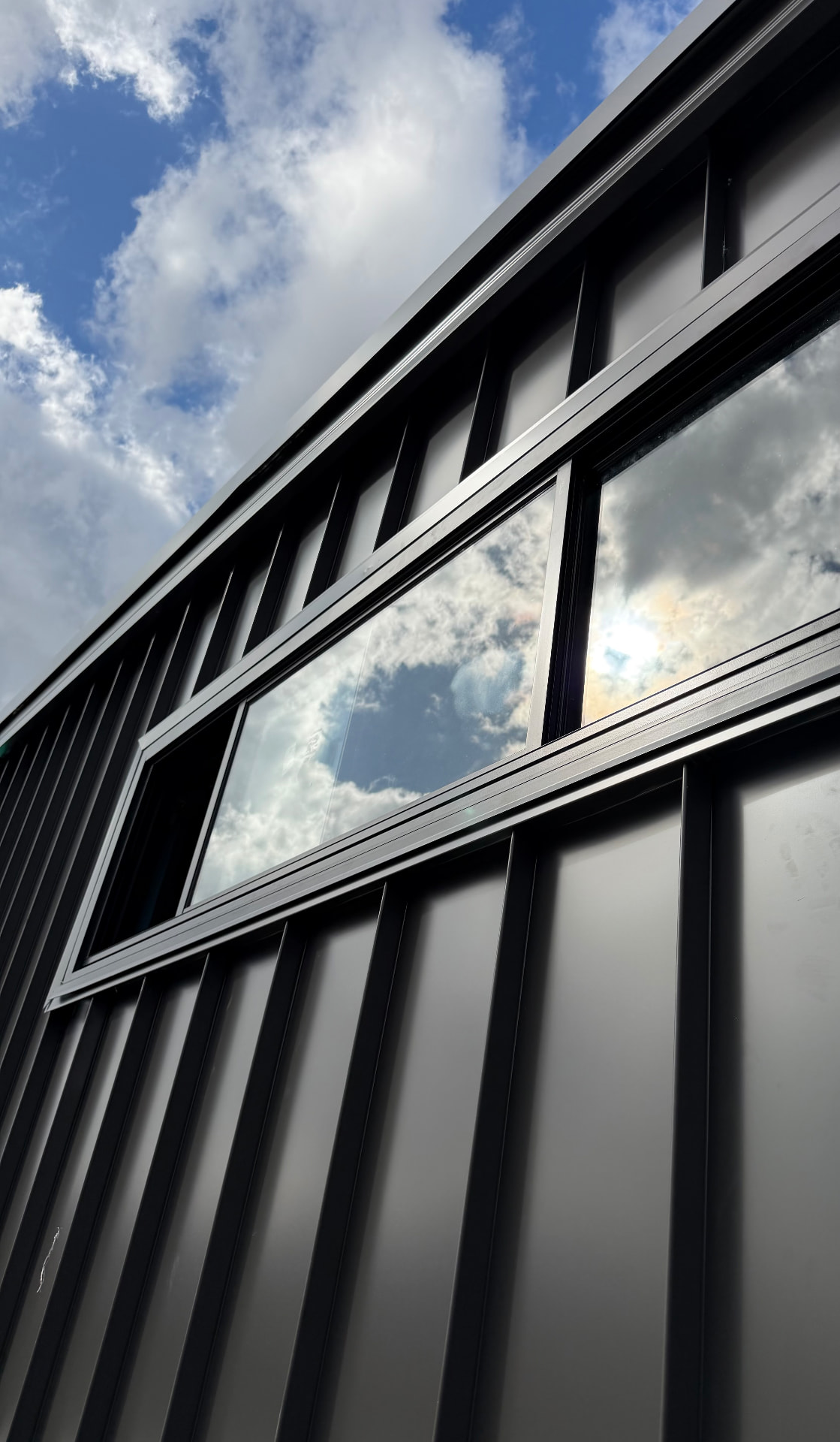 Black standing seam metal wall cladding with an angled window reveal, installed by Marvel Roofing Projects in Sydney